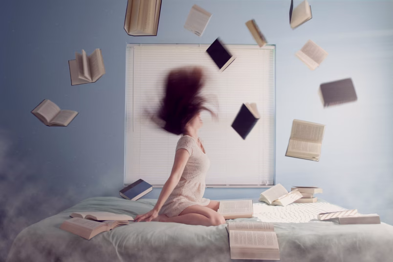 Woman on bed and books in the air